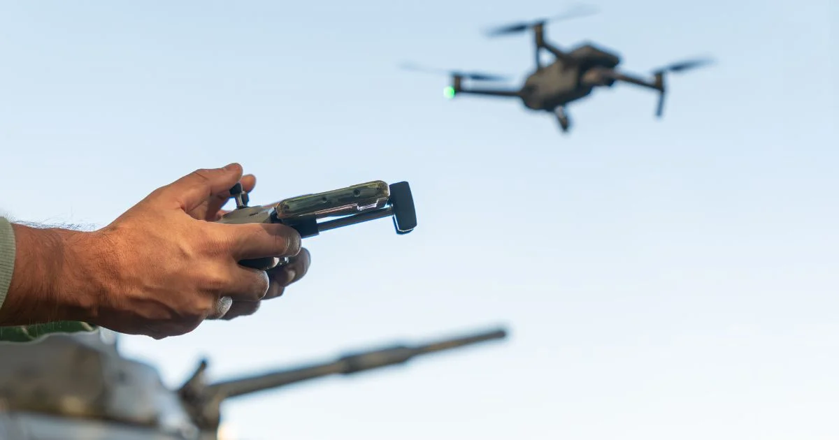 Man controlling drone with handheld remote outdoors.